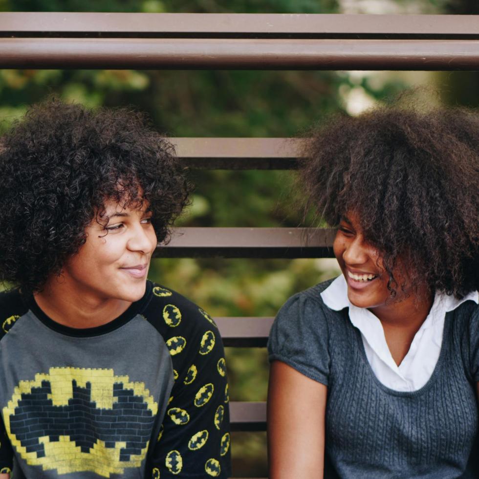 Photo of two black women smiling on a bench