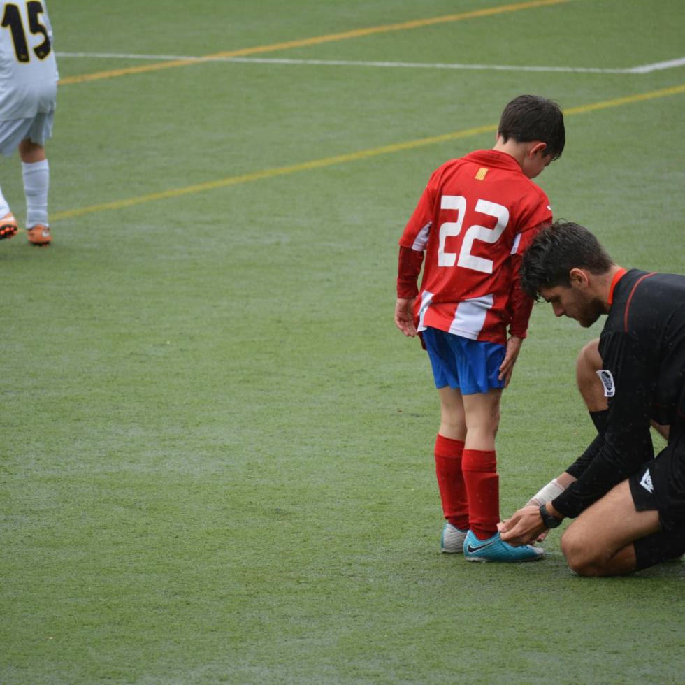 A soccer coach tying the shoe of a player on the field