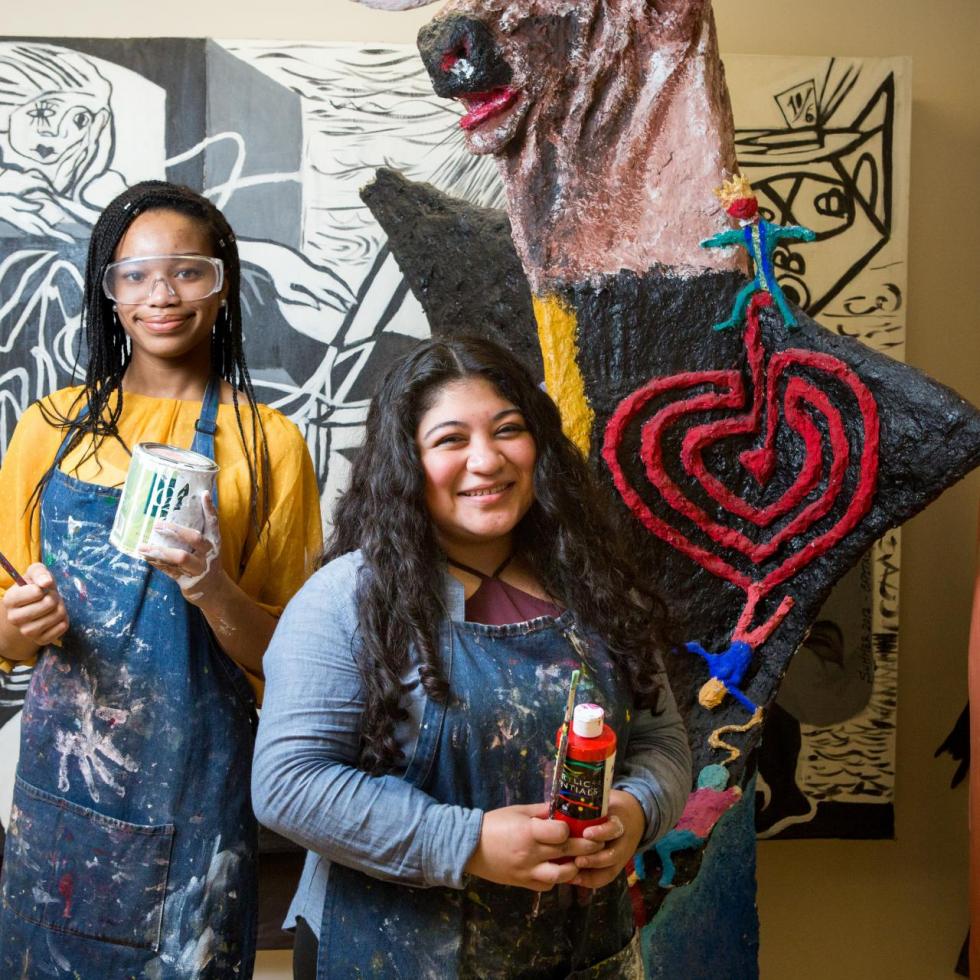 Photo of 2 girl artists showing off their mural and art projects