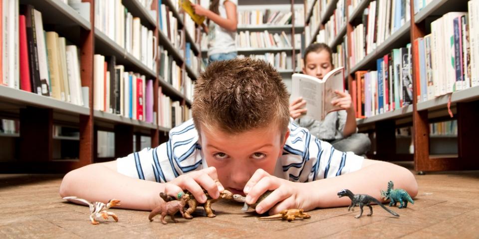 Student in a library playing with dinosaurs