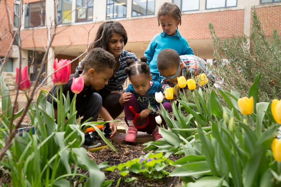 Children and adult observing flowers in a garden. 