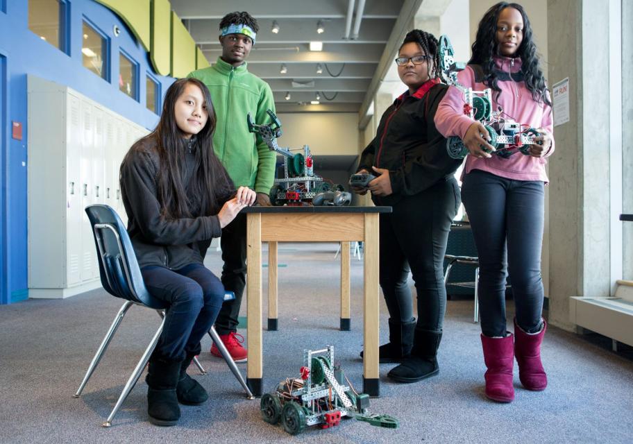 Four students standing around a table