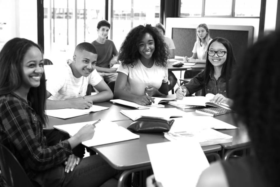Black and white picture of students surrounding a table smiling
