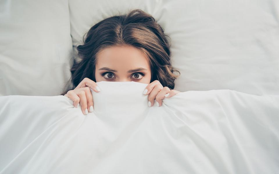 Woman hiding under a blanket