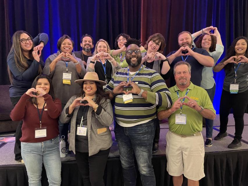 Image of the CAN and ASAPconnect teams making hearts shapes with their hands. 