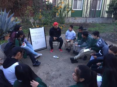 Group of students gathered around in a circle outside.