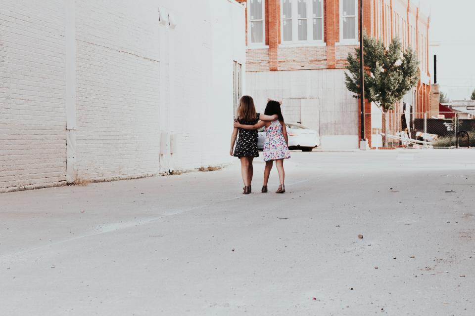 Two girls with their backs turned with their arms around each other