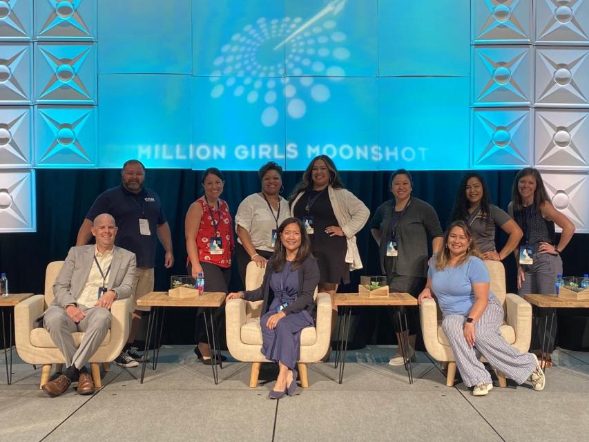 CA team standing on stage for a team photo with the blue Million girls Moonshot background