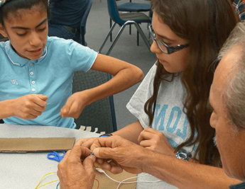 Two students and a teacher working on a STEAM project.