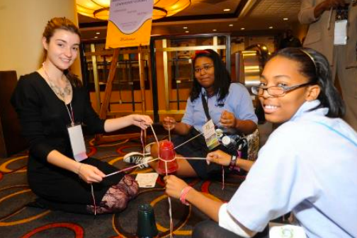 Three girls sitting around a solar system replica