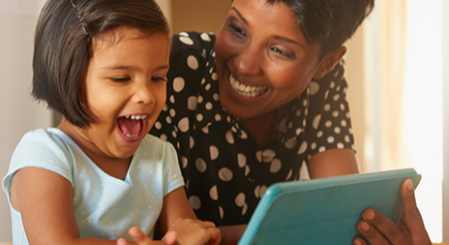 Child and adult looking at tablet together