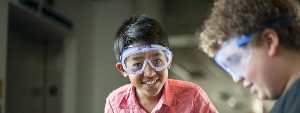 Two students wearing safety goggles working on an experiment