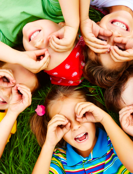 Children smiling looking into the camera covering their eyes