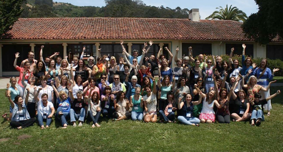 Photo of prior cohort smiling sitting in grass