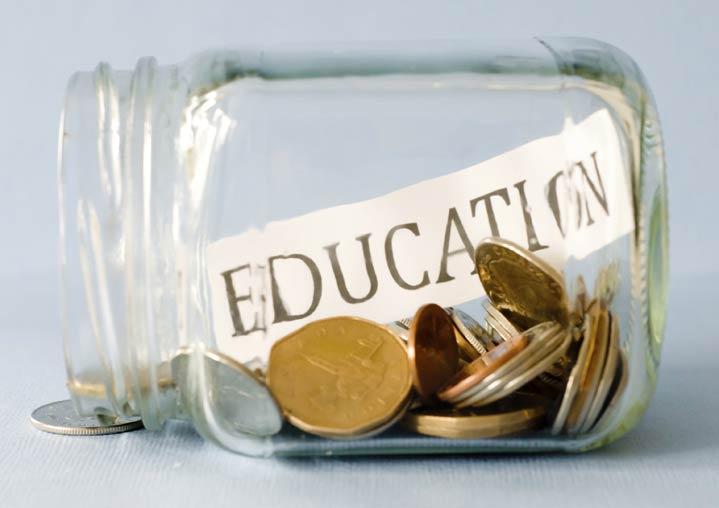Clear glass jar on it's side with coins inside it and a strip of paper that says "Education"