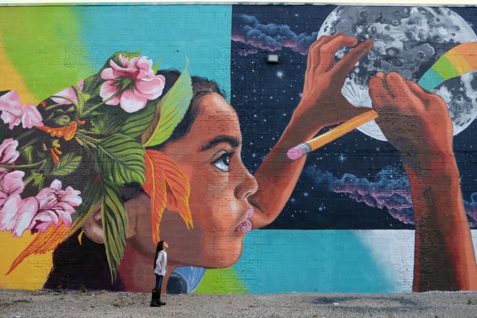 Young girl looking at a mural of a young girl