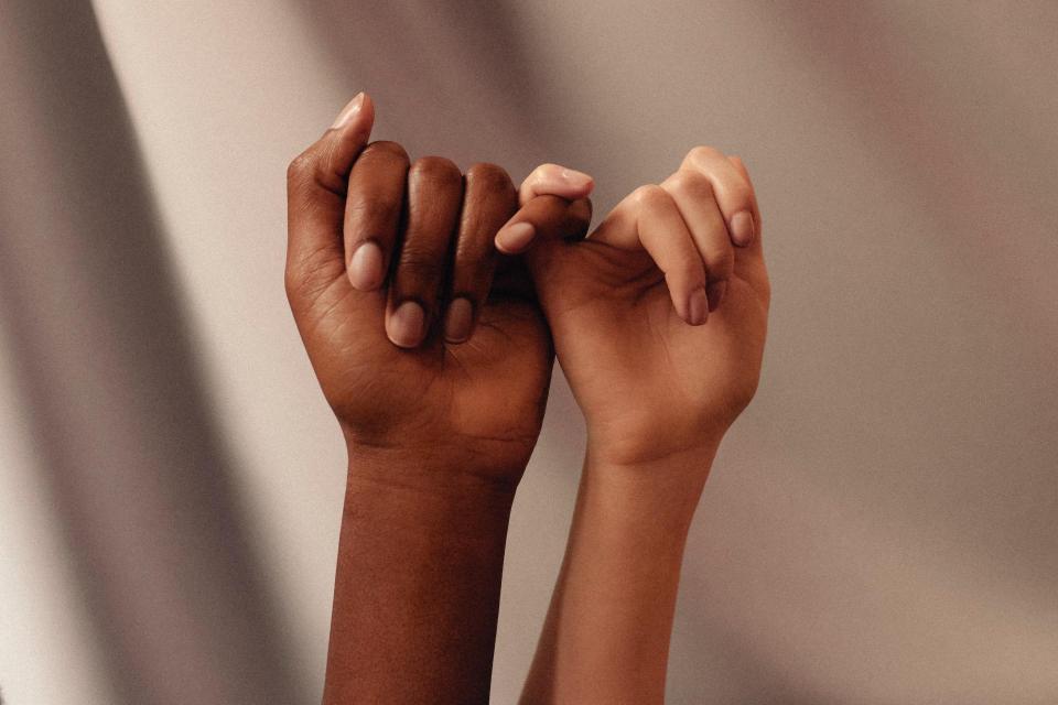 Photo of two hands holding pinkies