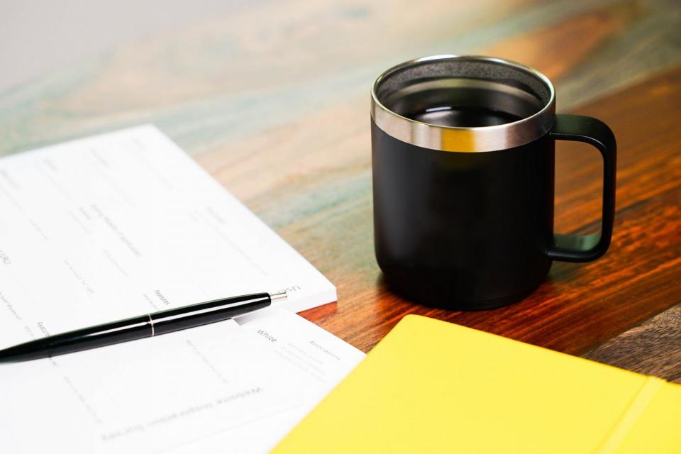 image of folders, coffee mug and papers on a wooden table surface