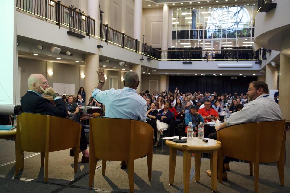 Participants sitting in the galleria Library while panelists are on stage in a fireside chat