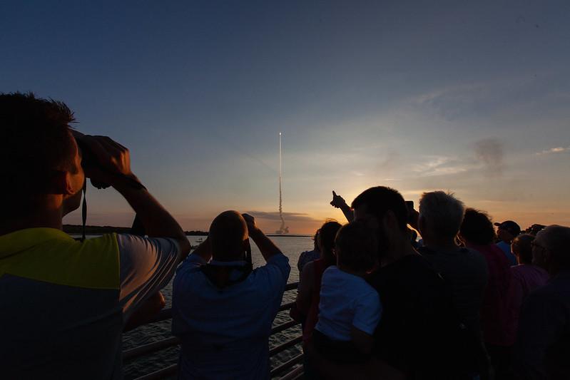 people gathering to watch the launch of a space shuttle 
