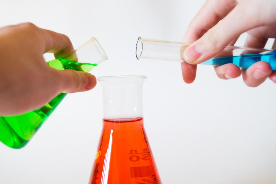 Two beakers being poured into another beaker