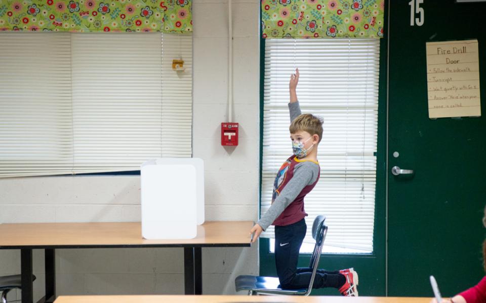 Student raising hand in a classroom.