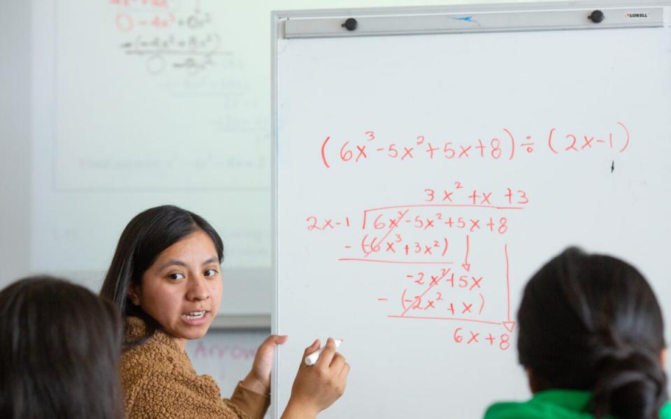 Girl teaching two other students how to solve a math problem