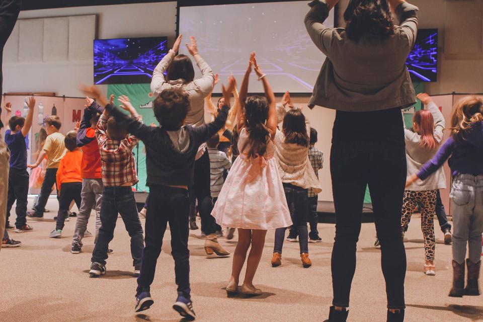 children and teachers in gymnasium doing jumping jacks