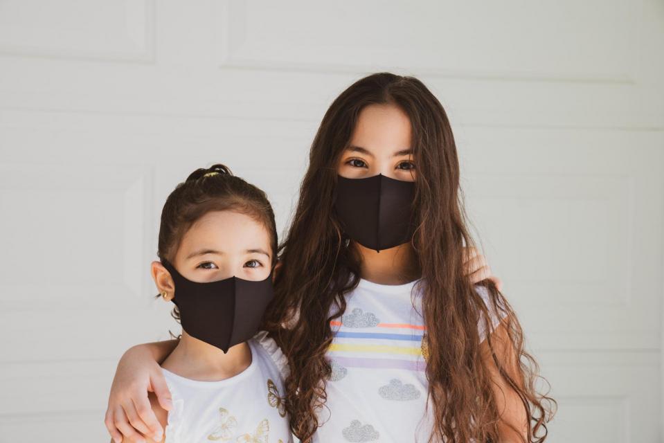 two girls wearing masks looking at camera