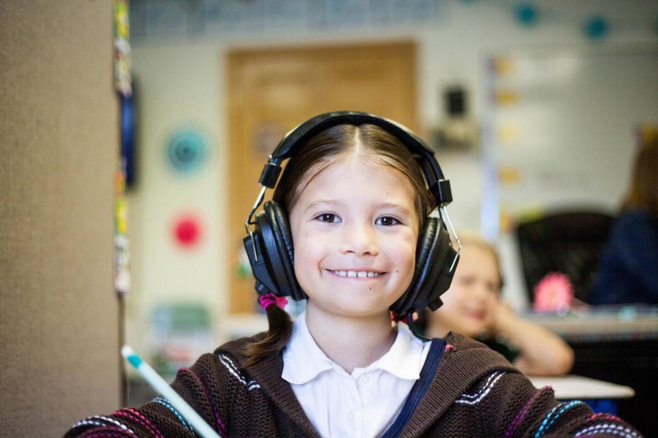 Child smiling and wearing headphones. 