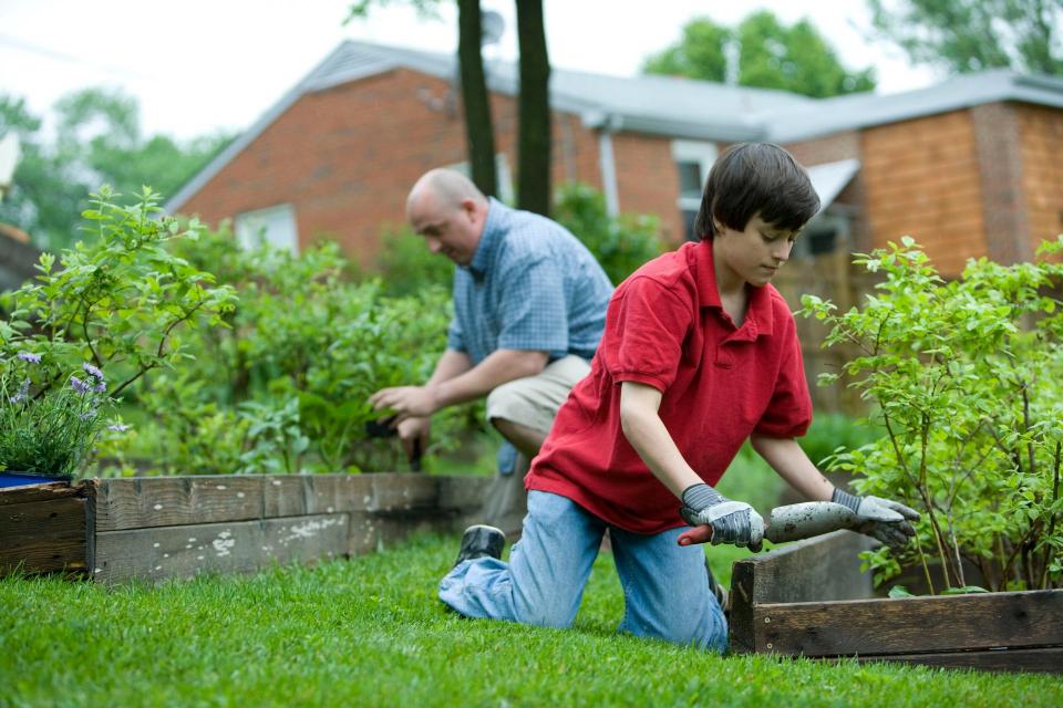boy in red polo and man in blue polo gardening