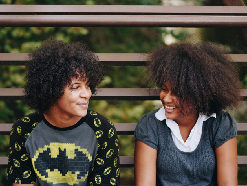 Photo of two black women smiling on a bench