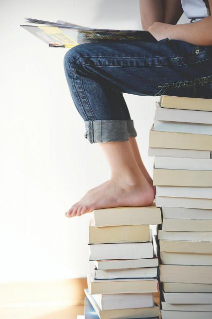 person sitting on top of a pile of books