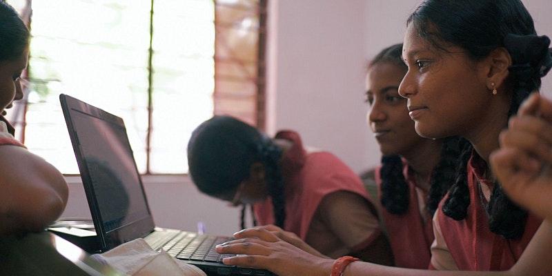 Three girls sitting together looking at a laptop