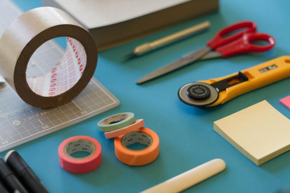 Table with a roll of tape, box cutter, scissors, and pencils