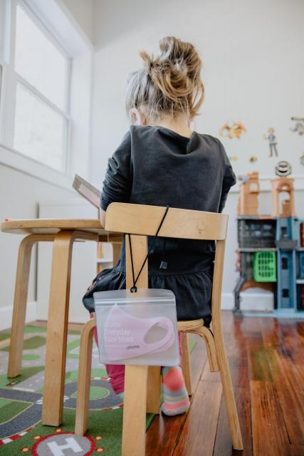 girl student working on a chair with a mask hanging off the chair