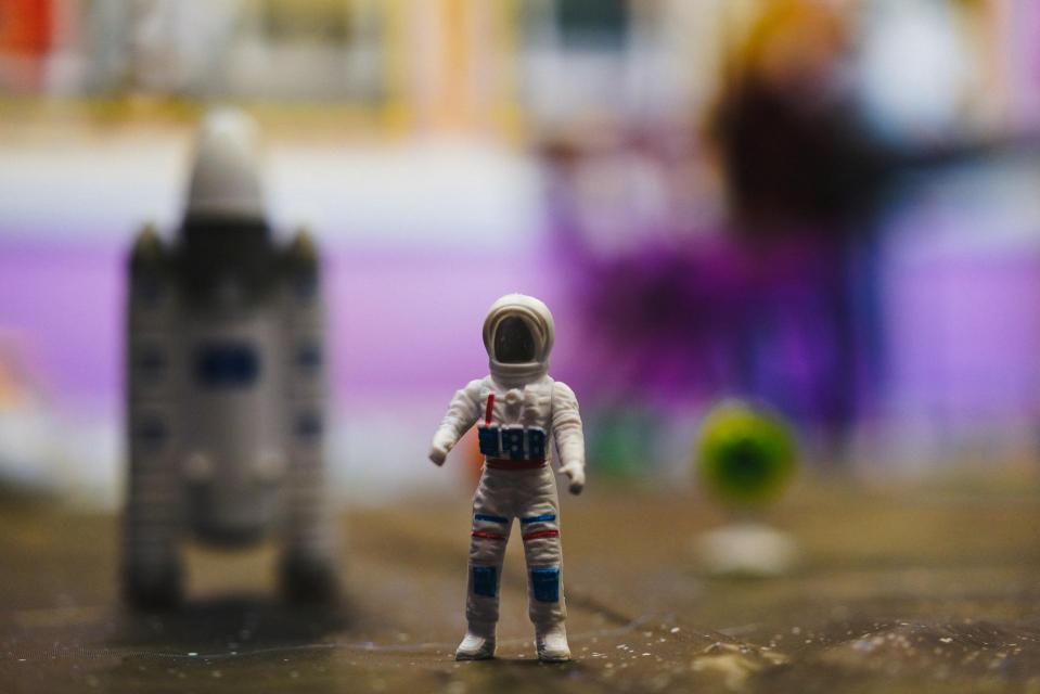 A clay astronaut with a spaceship behind it