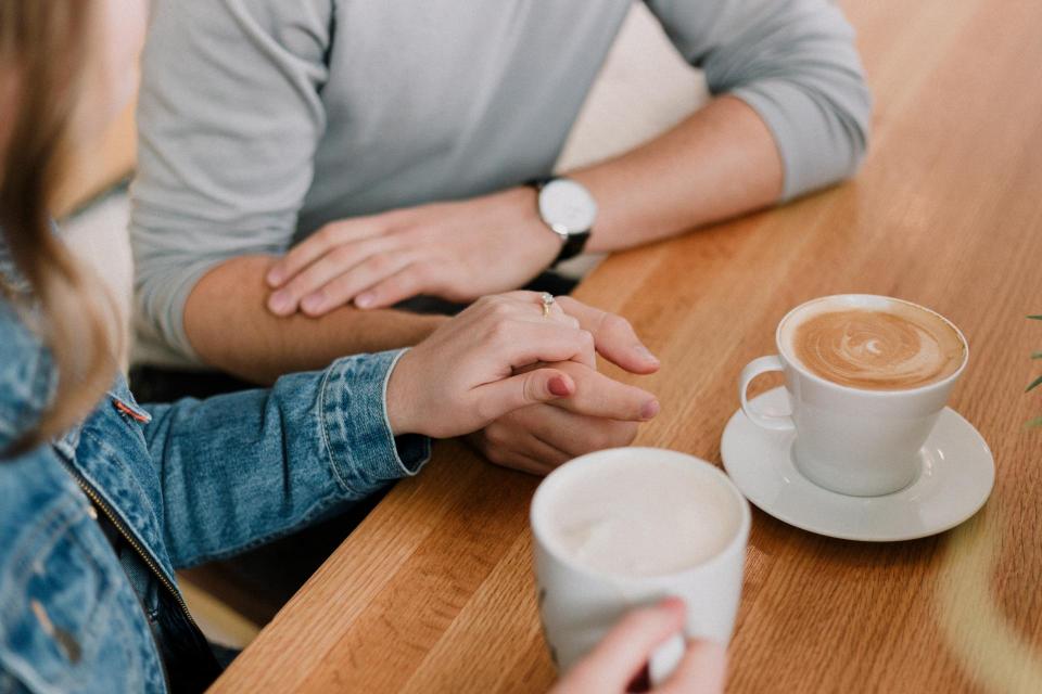 friend holding other friend's hand at a coffee table 