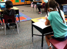 Children in an elementary classroom working on assignments at their desks.