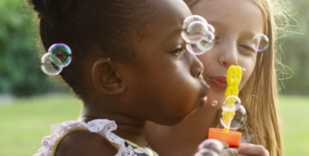 Two girls blowing bubbles outside