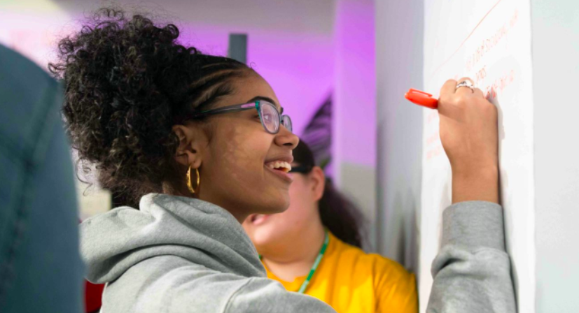 Girl smiling and writing on the whiteboard