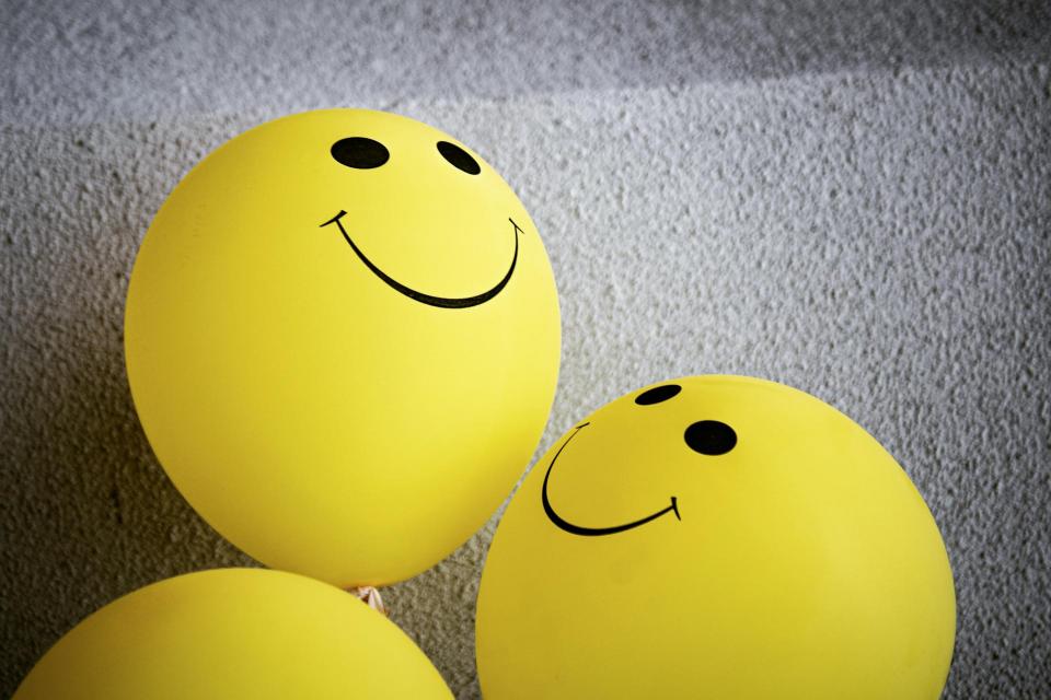 Two yellow balloons with smiles on them