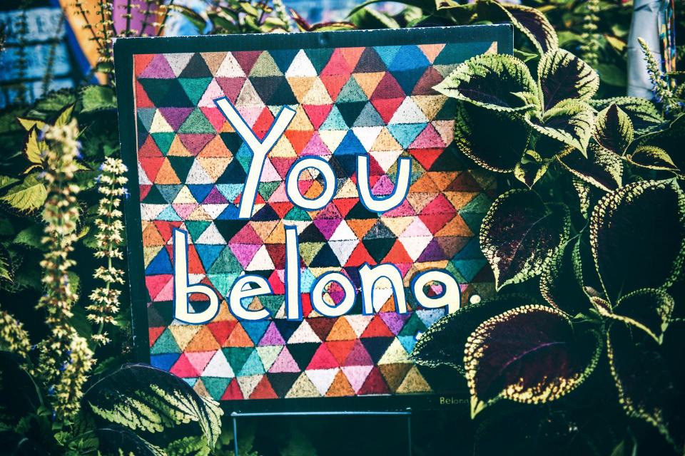 A colorful sign with the words "You belong"
